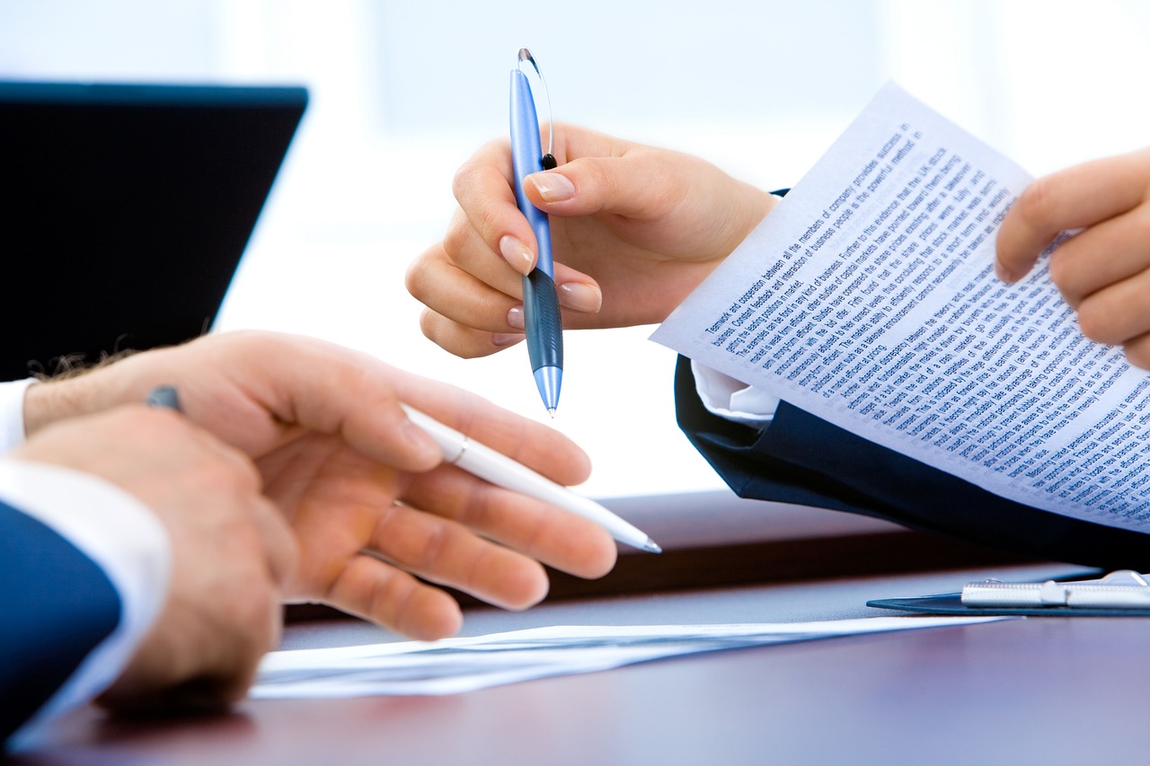 Close-up of hands with pens reviewing visa application documents and work permit forms